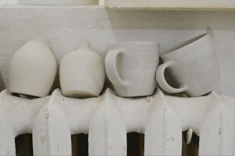 several clay pottery pieces drying on top of a household radiator